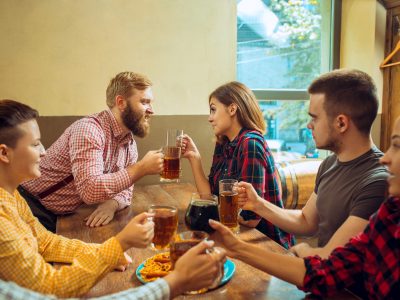 The people, leisure, friendship and communication concept - happy friends drinking beer, talking and clinking glasses at bar or pub and making selfie photo by mobile phone.